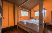 Chambre à l'intérieur de la tente safari Forest Park 't Wolfsven 13 avec lit double et cadre en bois aux Pays-Bas.