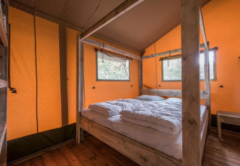 Chambre à l'intérieur de la tente safari Forest Park 't Wolfsven 13 avec lit double et cadre en bois aux Pays-Bas.