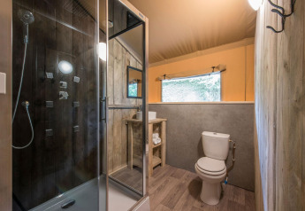 Salle de bain dans une tente safari à Forest Park 't Wolfsven 13, Pays-Bas, avec douche et toilettes.