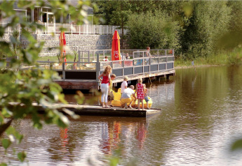 Famille sur un radeau flottant au bord d’un lac devant un café en plein air, à Forest Park 't Wolfsven.