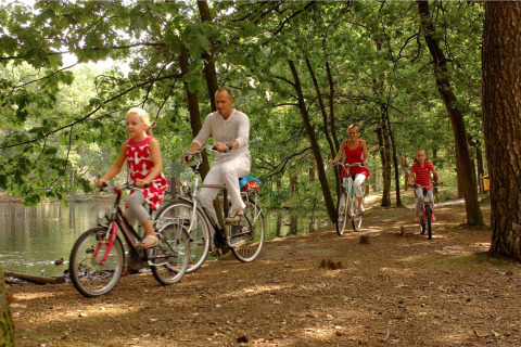 Familie cykler sammen i skovparken nær søen ved safari telt Forest Park ’t Wolfsven 13 i Holland.