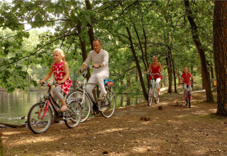 Familia pasea en bicicleta junto al lago y árboles cerca de la tienda Forest Park 't Wolfsven 13 en Países Bajos.