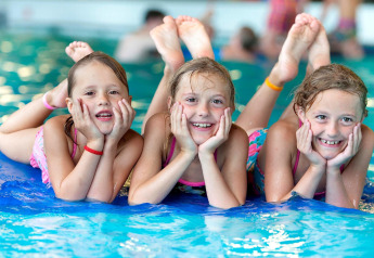 Trois enfants souriants en maillot de bain sur un matelas à la piscine de Forest Park 't Wolfsven 13.