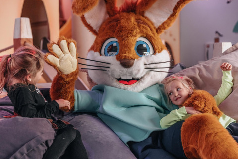Zwei Kinder spielen mit einem großen Hasenkostüm in einem gemütlichen Safarizelt im Forest Park 't Wolfsven, Niederlande.