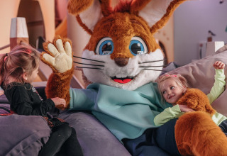To børn leger med en stor kaninmaskot inde i en hyggelig safaritelt i Forest Park 't Wolfsven, Holland.