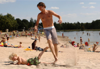 Homme joue avec un enfant dans le sable, familles profitent du lac à Forest Park 't Wolfsven 13 aux Pays-Bas.