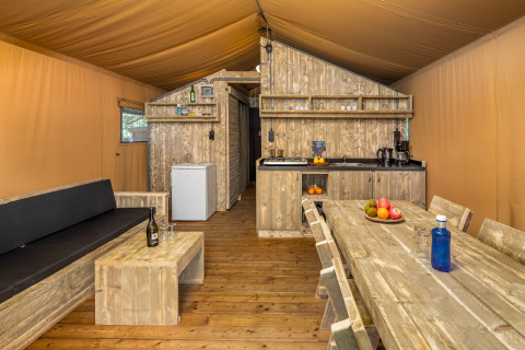 Vue intérieure de la tente safari Forest Park 't Wolfsven 12 aux Pays-Bas, avec mobilier en bois.