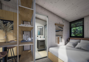 Intérieur d'une tiny house moderne au Holiday Park Klein Vink 23 aux Pays-Bas, avec chambre, salle de bains et cuisine.
