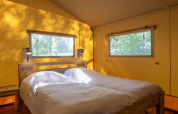 Dormitorio en tienda safari en Holiday Park «Klein Vink 21», Países Bajos, con dos camas individuales y luz.