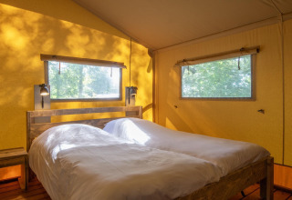 Cozy safari tent bedroom at Holiday Park «Klein Vink 21» in the Netherlands with two single beds, sunlight.