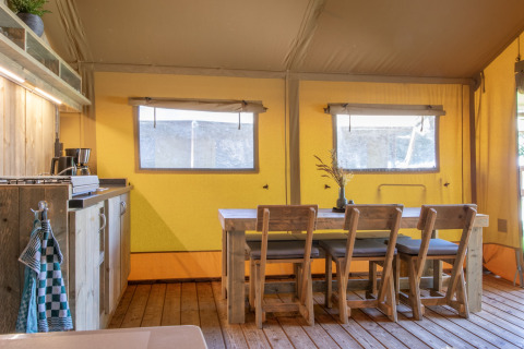 Indvendigt billede af et safari-telt med træmøbler, spisebord og hyggelig køkkenindretning i Holland.
