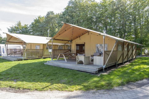 Tienda safari en Holiday Park Klein Vink 21, Países Bajos, con terraza de madera y muebles exteriores.