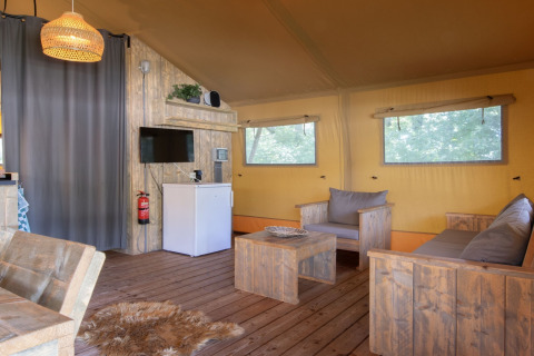 Innenraum eines Safari-Zeltes im Holiday Park Klein Vink 21 mit Holzfußboden und bequemen Sitzmöbeln.