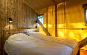 Dormitorio en tienda safari en Holiday Park Klein Vink 20, Países Bajos, con madera y luz acogedora.