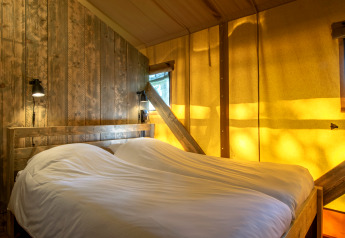 Dormitorio en tienda safari en Holiday Park Klein Vink 20, Países Bajos, con madera y luz acogedora.
