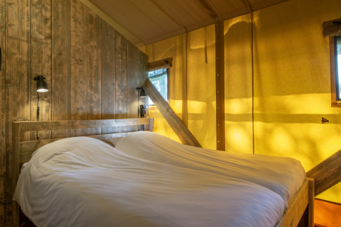Soveværelse i safari-telt ved Holiday Park Klein Vink 20, med trævægge og hyggelig belysning.