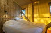 Dormitorio en tienda safari en Holiday Park Klein Vink 20, Países Bajos, con madera y luz acogedora.