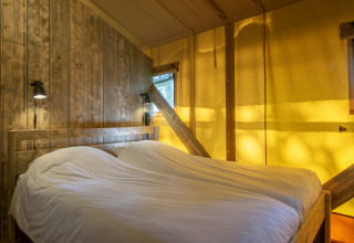Soveværelse i safari-telt ved Holiday Park Klein Vink 20, med trævægge og hyggelig belysning.