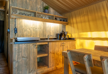 Cocina rústica de madera y comedor dentro de una tienda safari en Holiday Park Klein Vink, Países Bajos.