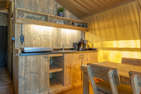 Rustic wooden kitchenette and dining area inside a safari tent at Holiday Park Klein Vink, Netherlands.