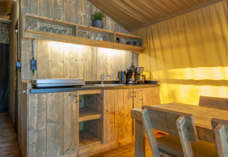 Cocina rústica de madera y comedor dentro de una tienda safari en Holiday Park Klein Vink, Países Bajos.