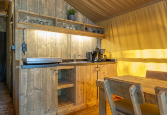 Cocina rústica de madera y comedor dentro de una tienda safari en Holiday Park Klein Vink, Países Bajos.