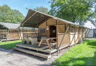 Safari-telt ved Holiday Park Klein Vink 20 i Holland med træterrasse, siddeområde og grønne omgivelser.
