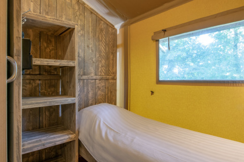 Cozy sleeping area in a safari tent at Holiday Park Klein Vink 21, Netherlands, with wood shelves.