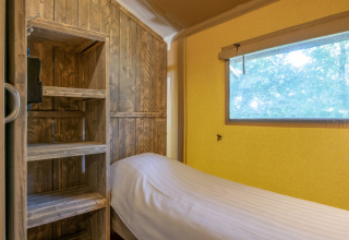 Cozy sleeping area in a safari tent at Holiday Park Klein Vink 21, Netherlands, with wood shelves.