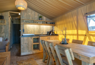 Indvendigt billede af et safari telt på Holiday Park Klein Vink 20, Holland, med træmøbler og køkken.
