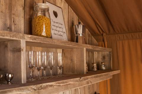 Mensola in legno in una cucina di tenda safari con bicchieri, barattolo di pasta, moka e spezie a Holiday Park Klein Vink 21.