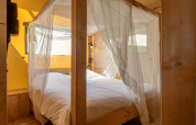Cama con mosquitera en una tienda safari en Holiday Park «Klein Vink 19», Países Bajos, con madera.