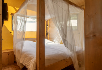 Cama con mosquitera en una tienda safari en Holiday Park «Klein Vink 19», Países Bajos, con madera.