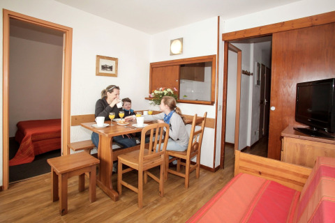 Family enjoys breakfast together at a wooden dining table in a cozy apartment at Holiday Park Klein Vink.
