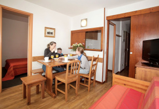 Familie sidder og spiser morgenmad ved et træbord i en hyggelig ferielejlighed i Holiday Park Klein Vink.