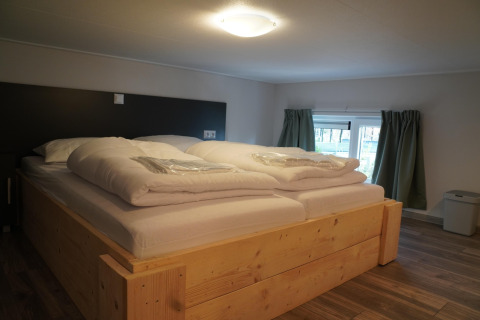 Schlafzimmer mit großem Bett im Tiny House Holiday Park De Rimboe & De Woeste Hoogte 41, Niederlande.