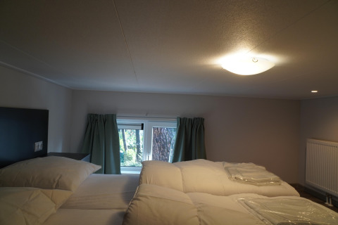 Schlafzimmer in einem Tiny House im Holiday Park De Rimboe & De Woeste Hoogte 41 mit niedriger Decke und Bett.