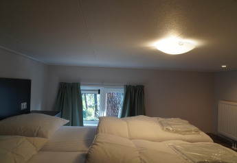Chambre dans une tiny house au Holiday Park De Rimboe & De Woeste Hoogte 41 avec plafond bas et lit double.