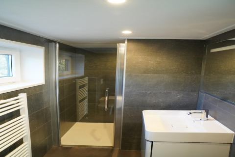 Bagno moderno e compatto con doccia, lavandino e finestra in una tiny house al Holiday Park De Rimboe.