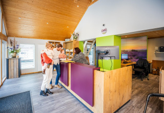 A family checks in at the reception of a cozy glamping accommodation with wood accents and modern decor.