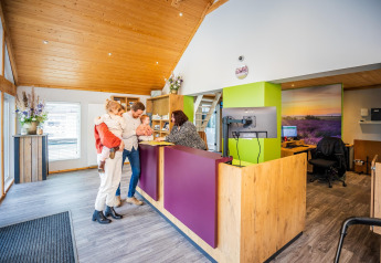 A family checks in at the reception of a cozy glamping accommodation with wood accents and modern decor.