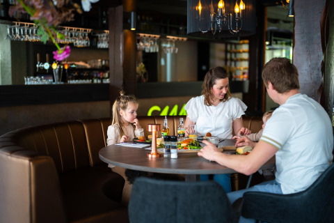 Familia compartiendo una comida en un elegante restaurante de un alojamiento glamping, ambiente cálido.