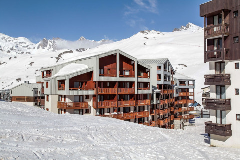 Edificios de apartamentos en una estación de esquí rodeados de montañas nevadas y cielos despejados.