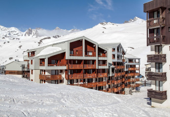 Ski resort apartment buildings in a snowy mountain landscape with blue sky and ski slopes in winter.