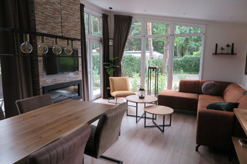 Sala de una moderna cabaña en Holiday Park De Rimboe & De Woeste Hoogte con grandes ventanales en Holanda.
