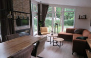 Modern lodge interior at Holiday Park De Rimboe & De Woeste Hoogte, spacious living area with large windows.