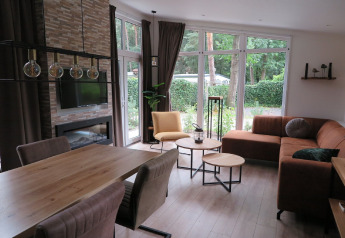 Modern lodge interior at Holiday Park De Rimboe & De Woeste Hoogte, spacious living area with large windows.