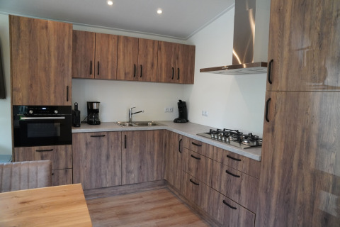 Modern wood-paneled kitchen at Holiday Park De Rimboe & De Woeste Hoogte 25, Netherlands, with stove and oven.