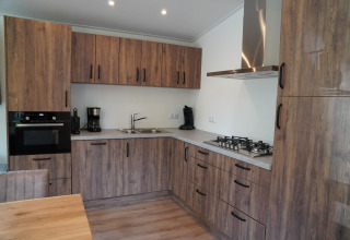 Cocina moderna revestida de madera en Holiday Park De Rimboe & De Woeste Hoogte 25, Países Bajos, con estufa y horno.