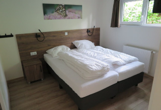 Bedroom with two single beds, white bedding, wooden floor, window, and butterfly painting on the wall.
